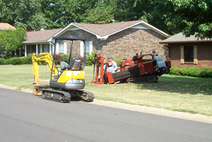 Workers in machines dig into the ground to investigate a residential water leak.